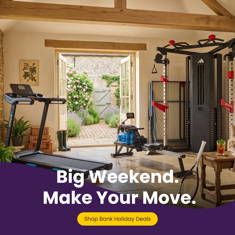 A home gym setup with a treadmill, rowing machine, and a large black multi-functional strength training gym machine, set in a rustic room with wooden beams and an open doorway leading to a garden. A purple banner at the bottom features the text 'Big Weekend.